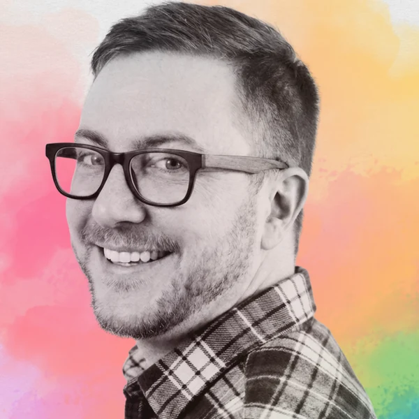 Brent Fisher smiling over one shoulder in a plaid flannel shirt and dark-rimmed glasses, photographed in black and white against a watercolor wash of pink, orange, yellow and green.